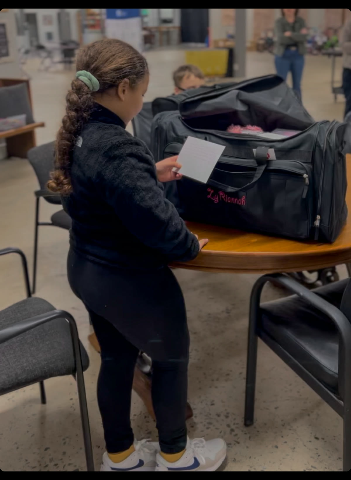 A child reads her note beside a packed Bag of Hope duffel at an LOTC event.