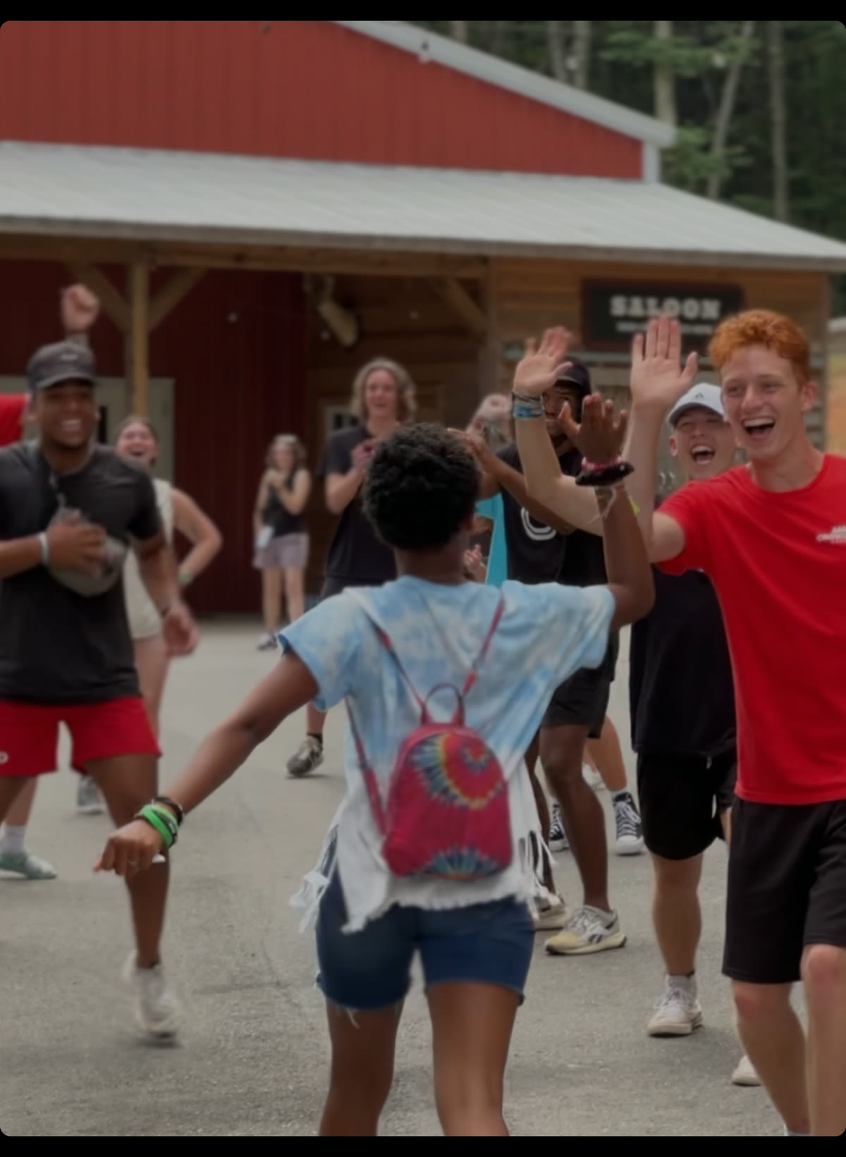 Campers cheering and high-fiving outdoors at Bridge Camp.