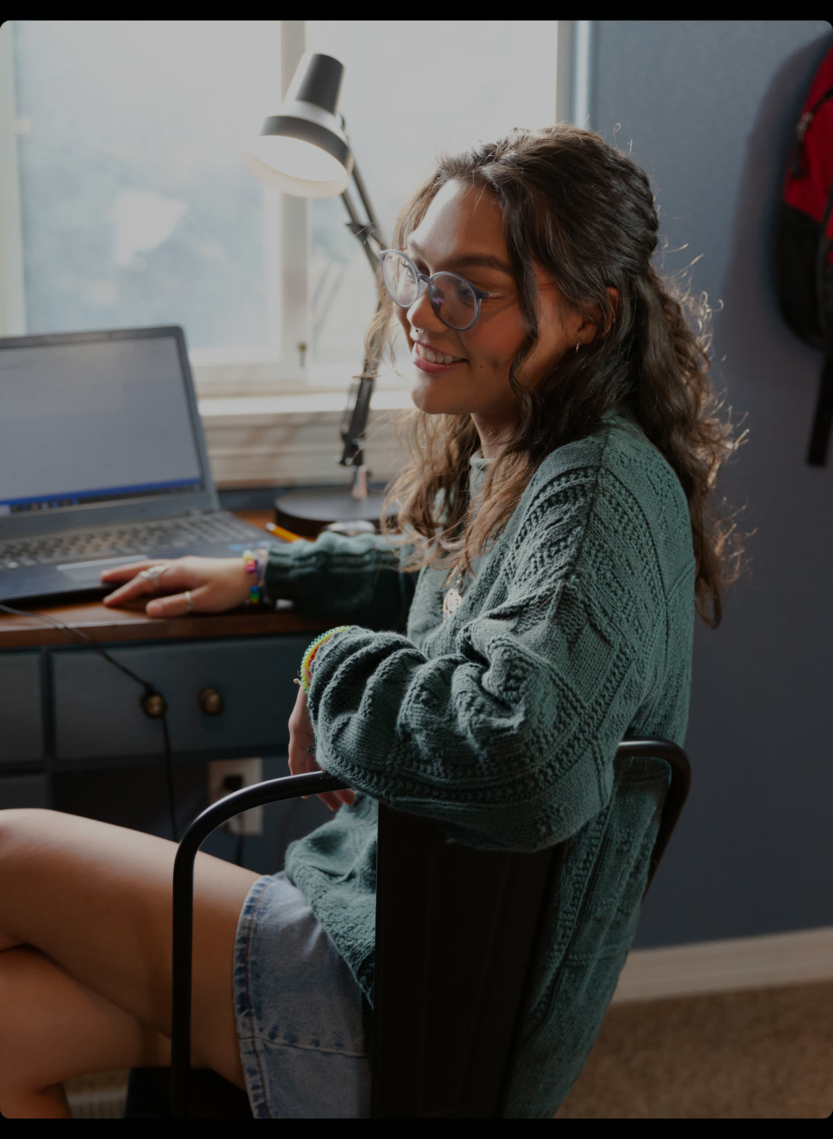 A young woman aging out of foster care studies at a laptop in her room.